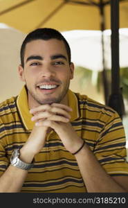 Portrait of a young man smiling with his hands clasped