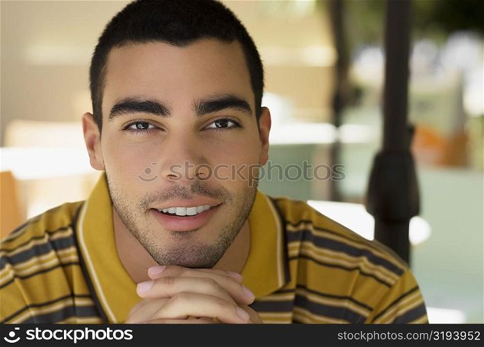 Portrait of a young man smiling with his hands clasped