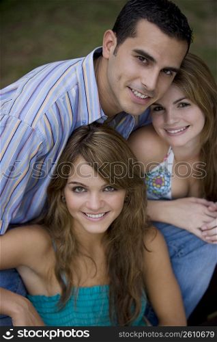 Portrait of a young man smiling with two young women