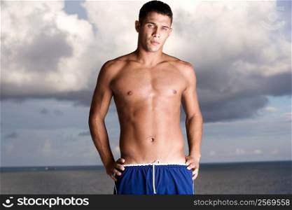 Portrait of a young man standing bare chested on the beach