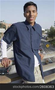 Portrait of a young man standing on an overpass and smiling