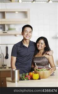 Portrait of a young man standing with a mid adult woman in the kitchen