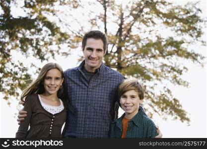 Portrait of a young man standing with his two children and smiling