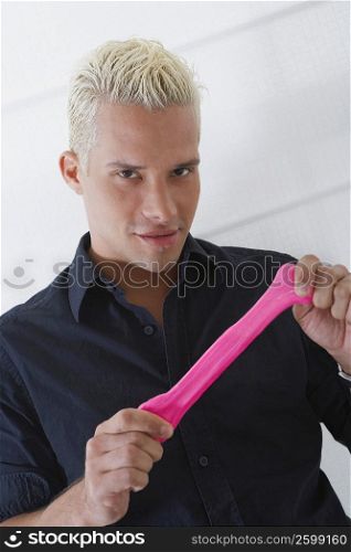 Portrait of a young man stretching a condom