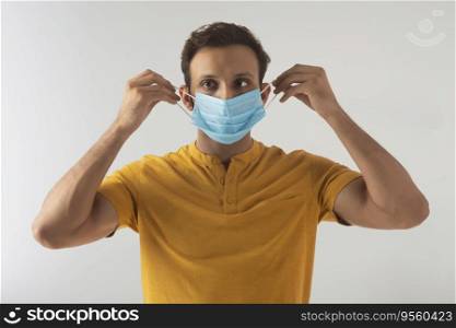 Portrait of a young man taking precautions by covering his face with a mask