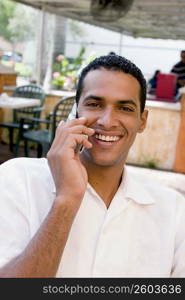 Portrait of a young man talking on a mobile phone and smiling