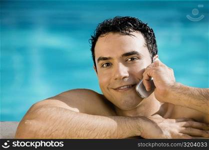 Portrait of a young man talking on a mobile phone in a swimming pool