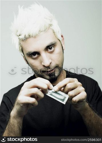 Portrait of a young man tearing a condom packet