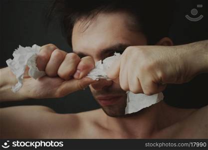 Portrait of a young man tearing paper
