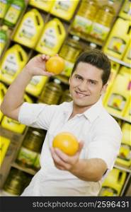 Portrait of a young man throwing an orange in a supermarket