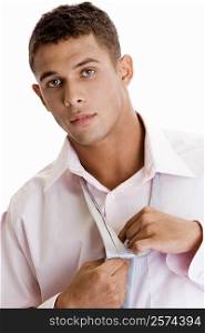 Portrait of a young man tying a necktie