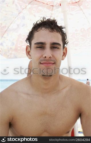 Portrait of a young man under a beach umbrella
