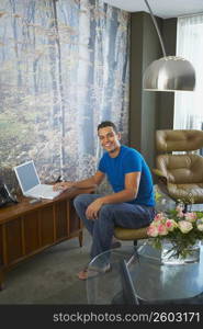 Portrait of a young man using a laptop and smiling