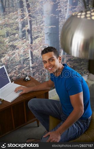Portrait of a young man using a laptop and smiling