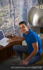 Portrait of a young man using a laptop and smiling