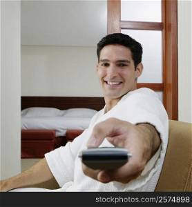 Portrait of a young man using a remote control and smiling