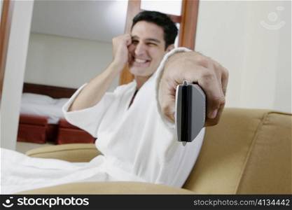 Portrait of a young man using a remote control and smiling