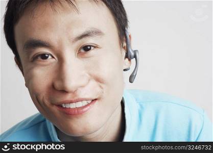 Portrait of a young man wearing a hands-free device and smiling