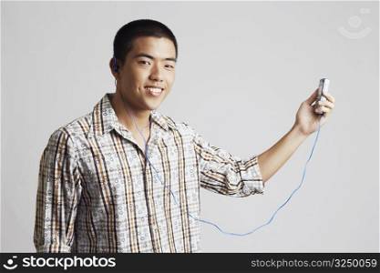 Portrait of a young man wearing headphones and holding a mobile phone