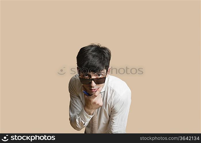 Portrait of a young man wearing sunglasses with hand on chin over colored background