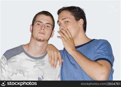 Portrait of a young man whispering into a young man&acute;s ear