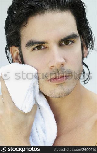 Portrait of a young man wiping his face with a towel