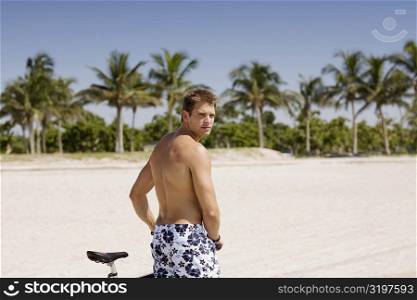 Portrait of a young man with a bicycle on the beach