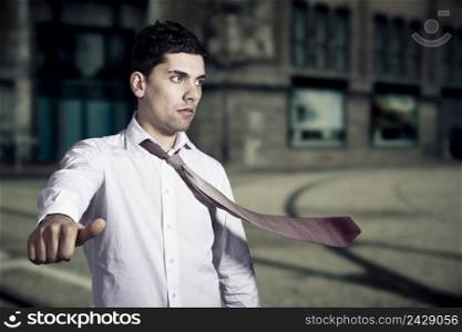 Portrait of a young man with a flying tie asking hitchhiking