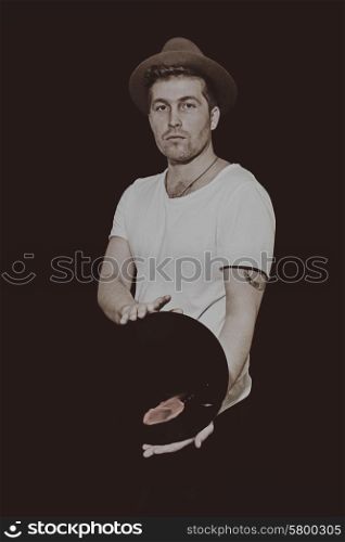 Portrait of a young man with a vinyl record on a black background