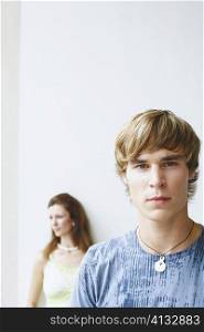 Portrait of a young man with a young woman behind him