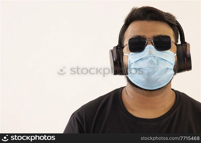 Portrait of a young man with headphones and mask on his face.