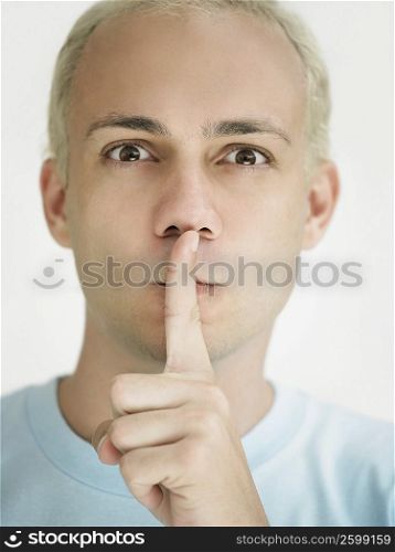 Portrait of a young man with his finger on his lips