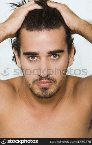 Portrait of a young man with his hands on his head