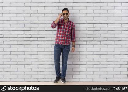 Portrait of a young man with sunglass standing against wall