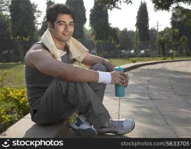 Portrait of a young man with towel round shoulders resting after workout