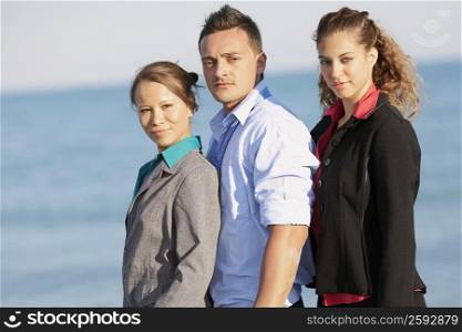 Portrait of a young man with two young women standing on the beach