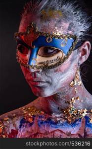 Portrait of a young masked woman with creative makeup on the theme of Venice Carnival. Creative podium makeup in Venetian lady style