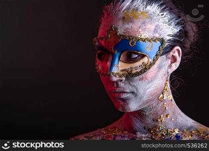 Portrait of a young masked woman with creative makeup on the theme of Venice Carnival. Creative podium makeup in Venetian lady style