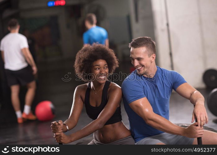 portrait of a young multiethnic couple after training with a sledgehammer and tractor tire