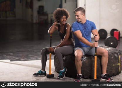 portrait of a young multiethnic couple after training with a sledgehammer and tractor tire