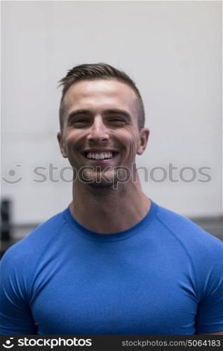 Portrait of a young muscular fitness trainer at the gym