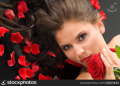 portrait of a young pretty woman with red rose and petals on hair