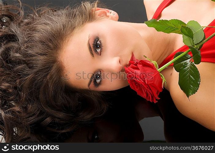 portrait of a young pretty woman with red rose on black background