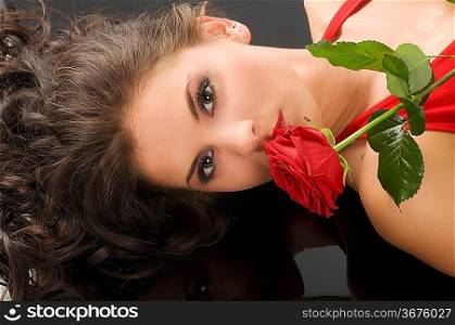 portrait of a young pretty woman with red rose on black background
