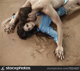 Portrait of a young sensual couple laying on the bright sand