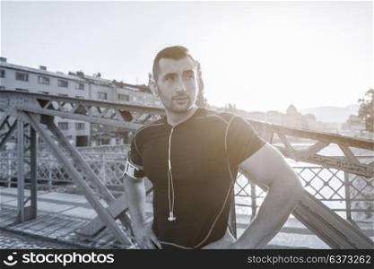 portrait of a young sporty jogging man at sunny morning in the city