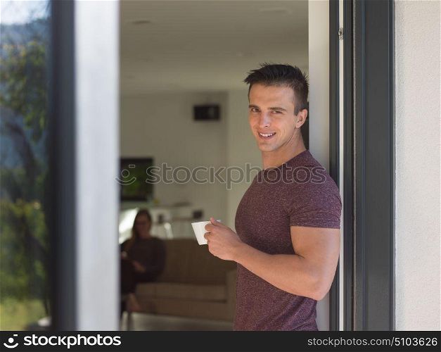 portrait of a young successful man drinking coffee in the doorway of his luxury home villa