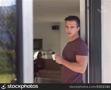 portrait of a young successful man drinking coffee in the doorway of his luxury home villa