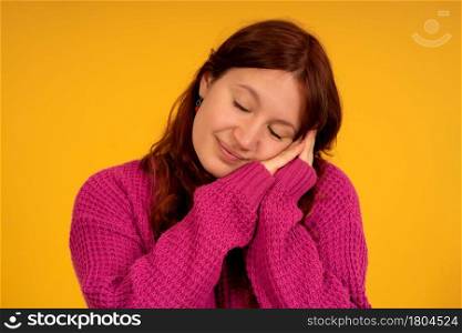 Portrait of a young tired woman posing with eyes closed while standing against an isolated background.