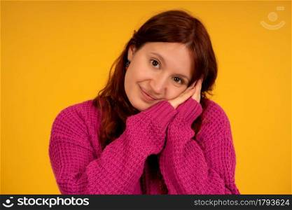 Portrait of a young tired woman posing with hands together at her face while standing against an isolated background.